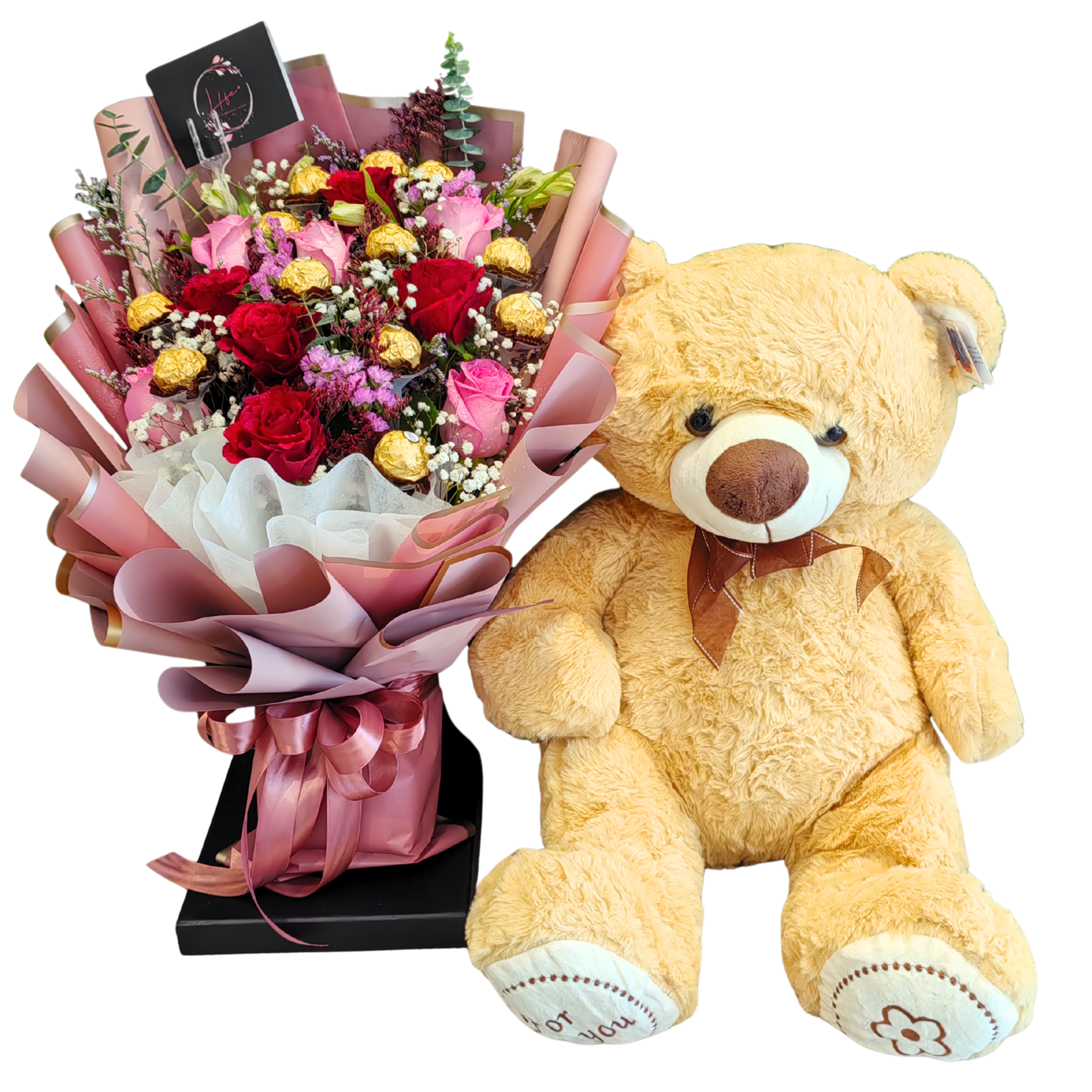 Sweetheart Serenade-- a floral arrangement featuring pink and red roses mix, with white gypsophila, pink statice, mixed color limonium, Ferrero Chocolate pops, and a touch of eucalyptus cinerea. Wrapped in pink and white floral paper, hand-tied with pink satin ribbon, and paired with light yellow teddy bear.