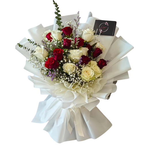 Bouquet of red and white roses with gypsophila, lilac limoniums, and eucalyptus, wrapped in white paper with ribbon—held for a romantic floral gift