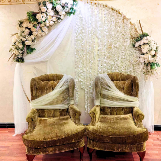 Hayat Flower's kosha floral arch over a pair of ornate chairs draped with white fabric.